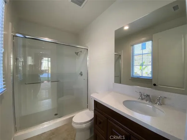 a bathroom with a shower sink vanity mirror and toilet