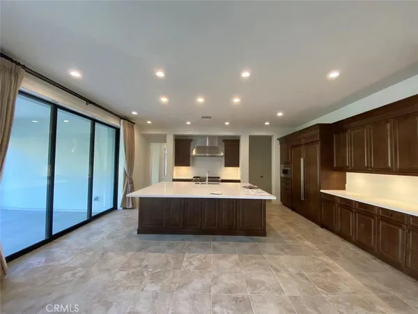 a view of kitchen with kitchen island granite countertop a refrigerator and a sink