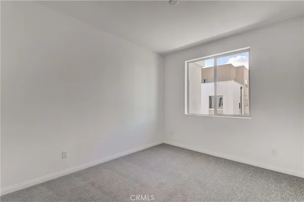 a view of an empty room with closet and a window