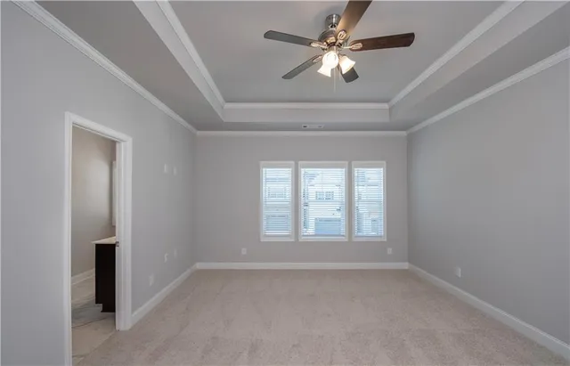 an empty room with a chandelier fan and windows