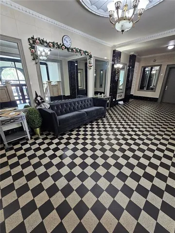a living room with a black white checkered floor with a gaming machine and dining space
