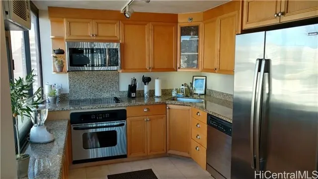 a kitchen with stainless steel appliances granite countertop a refrigerator a stove and a sink with wooden floor