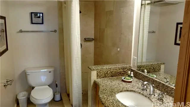 a bathroom with a granite countertop toilet sink and mirror