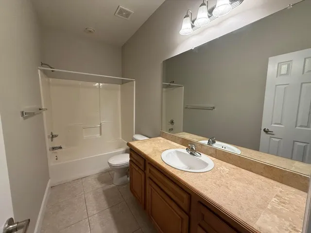 a bathroom with a granite countertop sink a toilet and shower