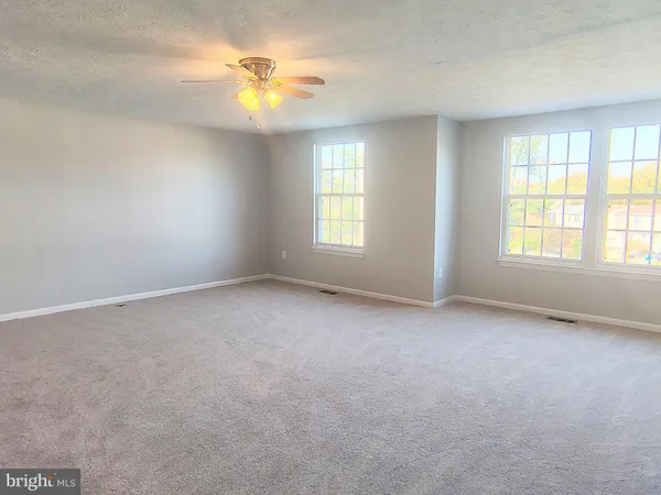 an empty room with a window and a ceiling fan