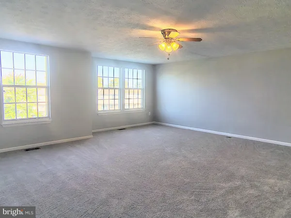 an empty room with windows and chandelier fan