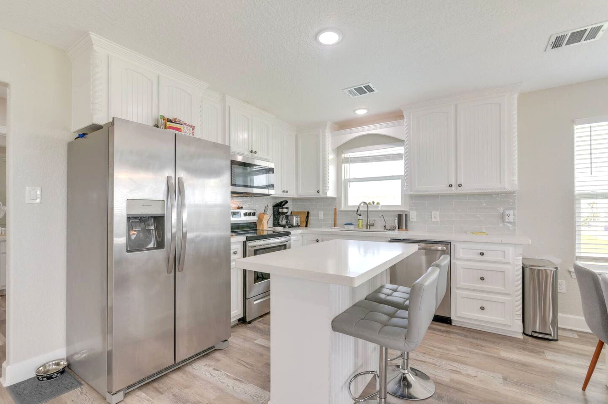315 Murex Street Surfside Beach, TX 77541 - Photo 8 of 29 a kitchen with stainless steel appliances granite countertop a refrigerator a stove a sink and white cabinets with wooden floor