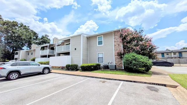 a view of a white house in front of a yard with potted plants