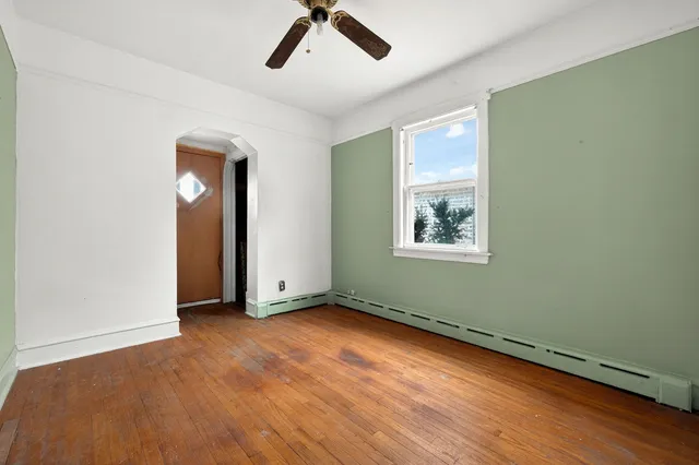 an empty room with wooden floor cabinet and windows