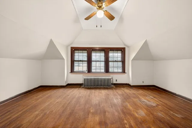 an empty room with wooden floor chandelier fan and windows