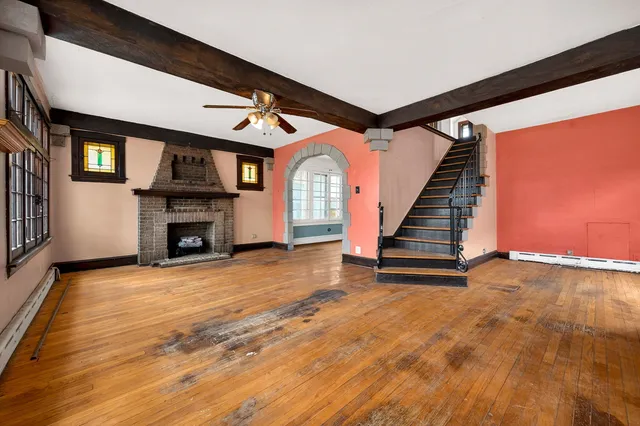 a view of an empty room with stairs a fireplace and stairs