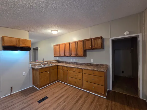 a kitchen with stainless steel appliances granite countertop a sink cabinets and wooden floor