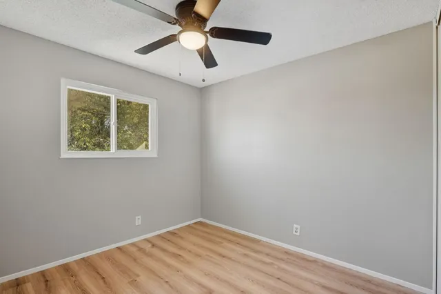 an empty room with a window and a ceiling fan