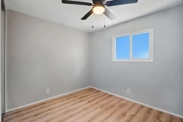 an empty room with a window and a fan
