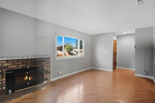 a view of an empty room with window and fire place