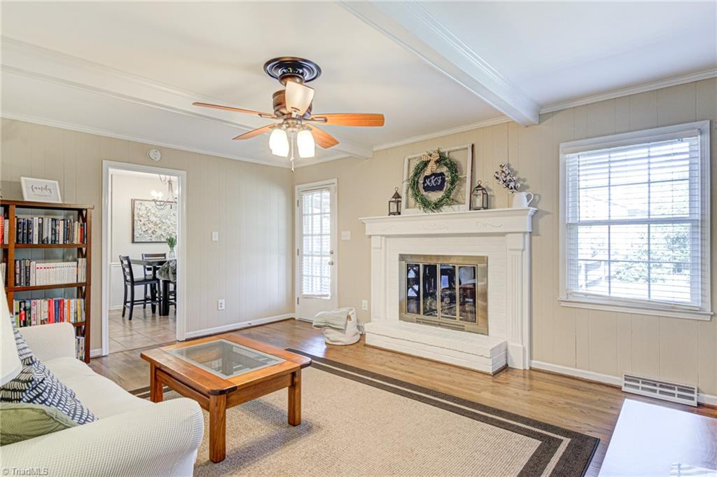 4516 Tower Road Greensboro, NC 27410 - Photo 15 of 26 Cozy Den with gas-log fireplace is tastefully on-trend with neutral painted paneling and crisp white architectural beams, brick, mantel and hearth. Den overlooks backyard and has direct access to covered deck.