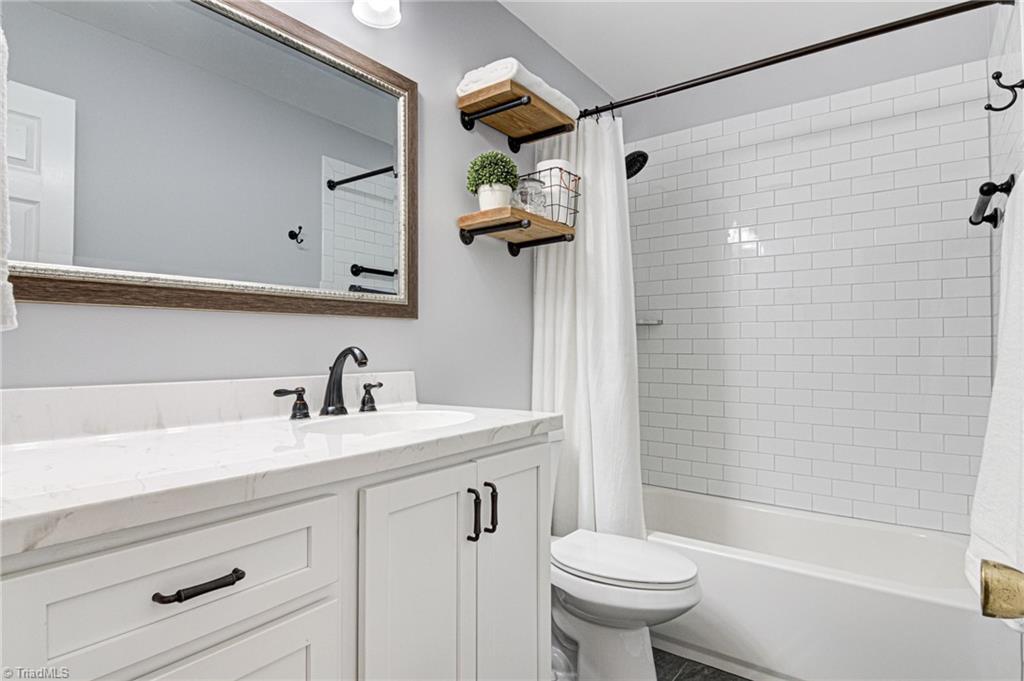 4516 Tower Road Greensboro, NC 27410 - Photo 21 of 26 Bathroom 2 is freshly renovated with white counters, cabinetry, and subway tile; plus, accent wood shelves