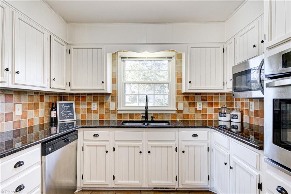 4516 Tower Road Greensboro, NC 27410 - Photo 7 of 26 Kitchen features original wood cabinets painted white, stainless appliances and black granite counters