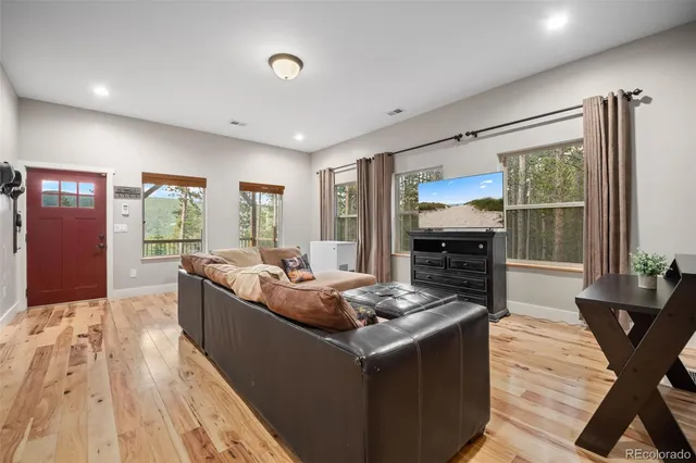 a living room with stainless steel appliances granite countertop furniture and a wooden floor