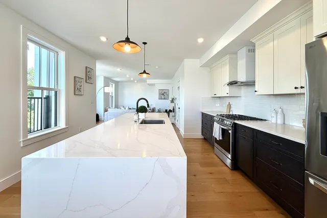 a kitchen with stainless steel appliances kitchen island granite countertop a refrigerator a stove a sink and a dining table with chairs