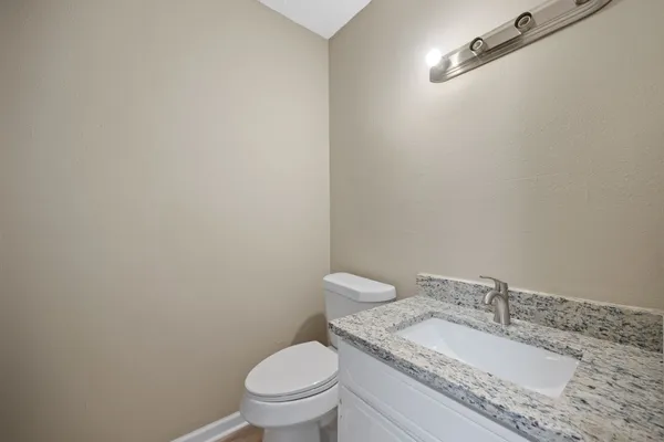 a bathroom with a granite countertop toilet and a sink