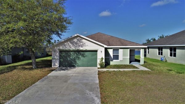 8180 Liriope Loop Lehigh Acres, FL 33972 - Photo 3 of 34 a front view of a house with a yard and porch