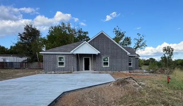 a front view of house with yard and trees in the background