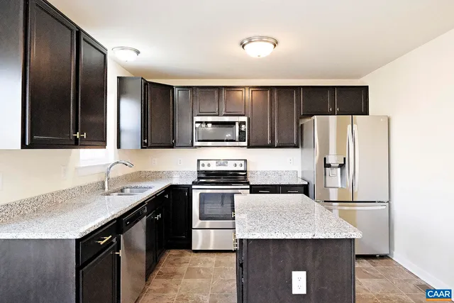 a kitchen with kitchen island granite countertop stainless steel appliances a sink and a refrigerator