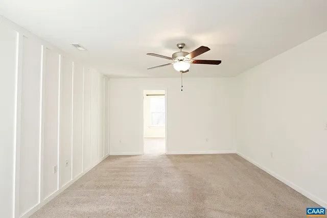 an empty room with a ceiling fan and a window