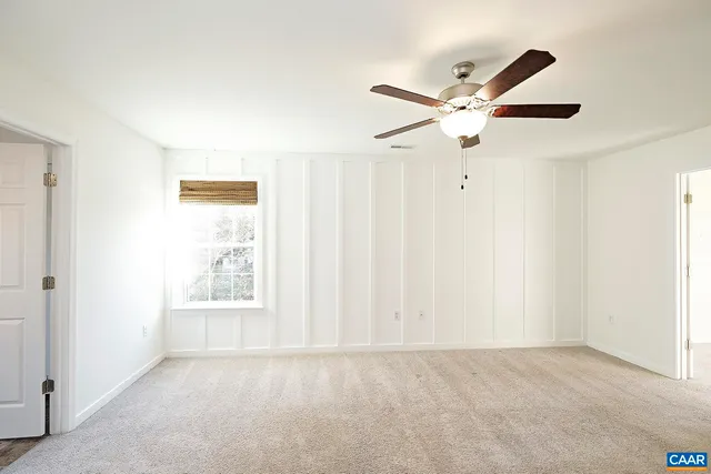an empty room with windows and fan