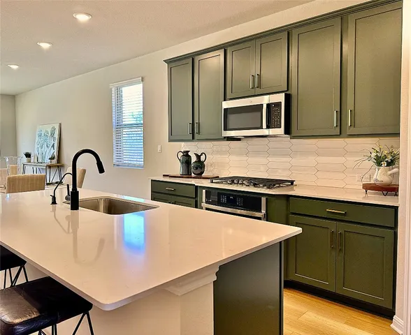 a kitchen with stainless steel appliances a stove a sink and a microwave