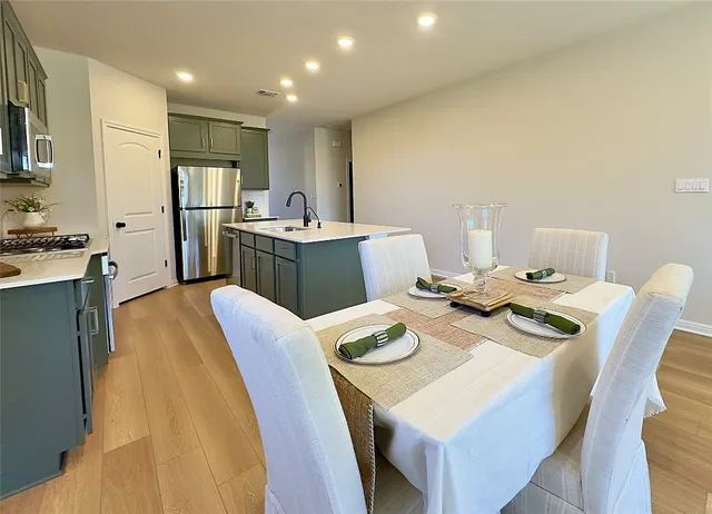 a kitchen with stainless steel appliances kitchen island granite countertop a sink a stove a refrigerator with a dining table and chairs