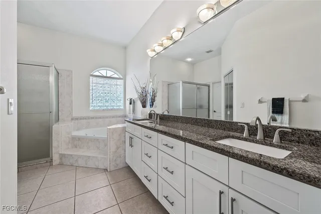 a bathroom with a granite countertop double vanity sink a mirror and a bathtub
