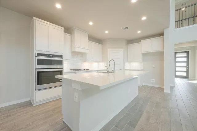 a kitchen with kitchen island white cabinets and stainless steel appliances