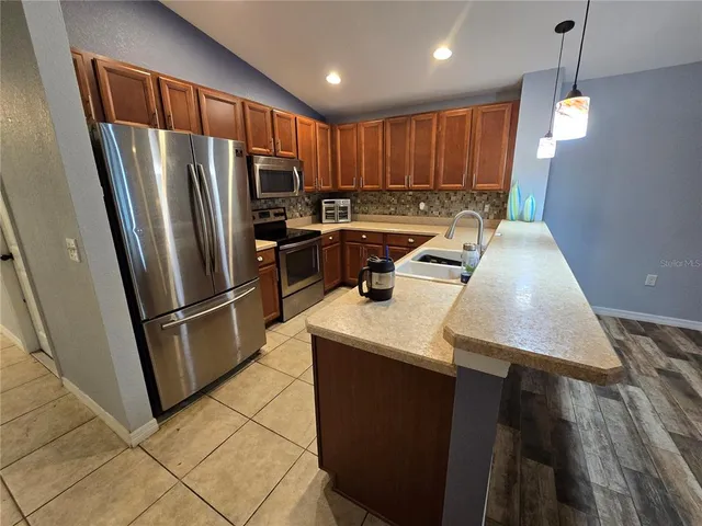 a kitchen with stainless steel appliances granite countertop a refrigerator a sink a stove a microwave and island