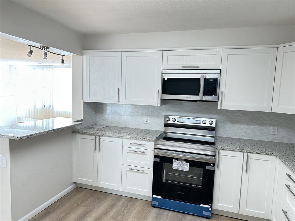 1004 Paradise Road, Unit 1K Swampscott, MA 01907 - Photo 11 of 37 a kitchen with granite countertop a stove and a microwave