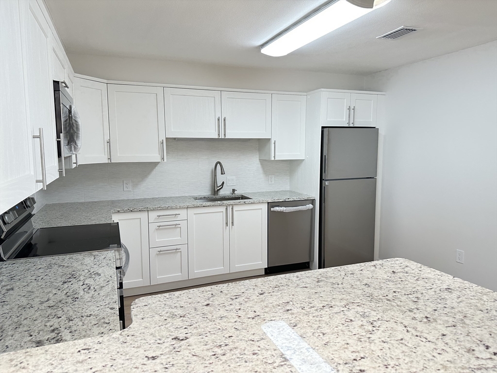 1004 Paradise Road, Unit 1K Swampscott, MA 01907 - Photo 12 of 37 a kitchen with a refrigerator sink and cabinets