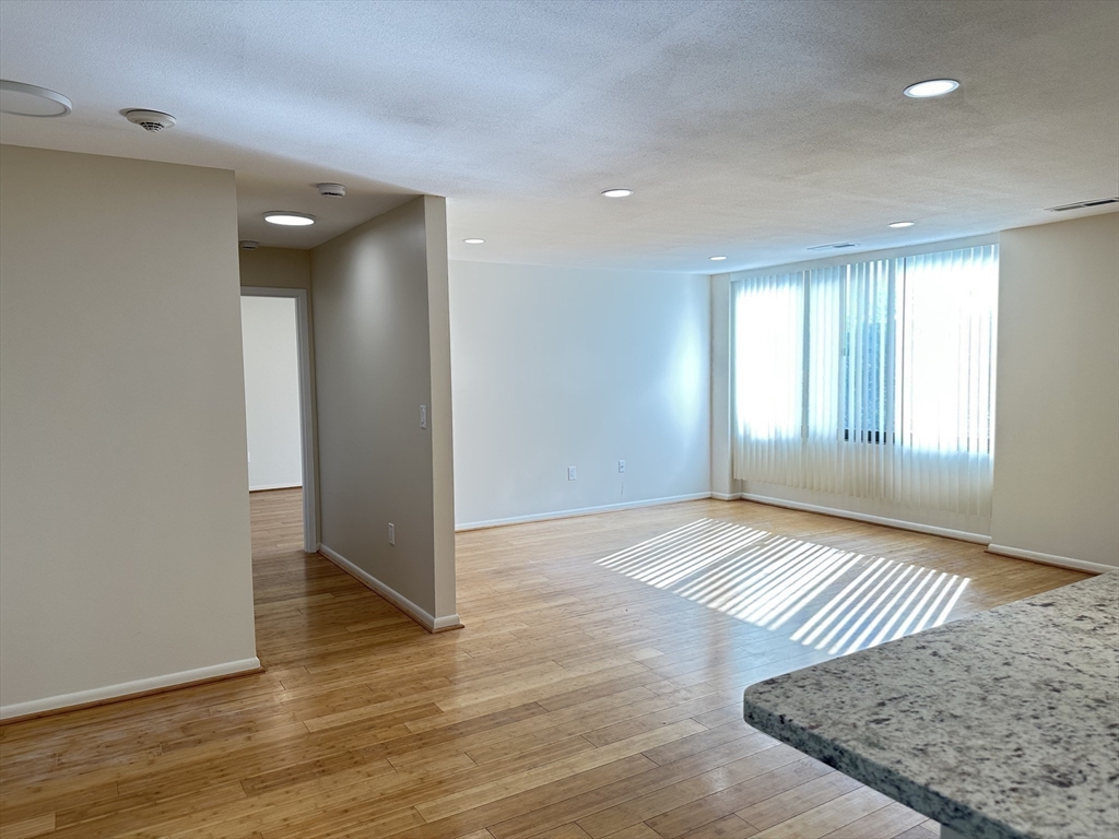 1004 Paradise Road, Unit 1K Swampscott, MA 01907 - Photo 14 of 37 an empty room with wooden floor and windows
