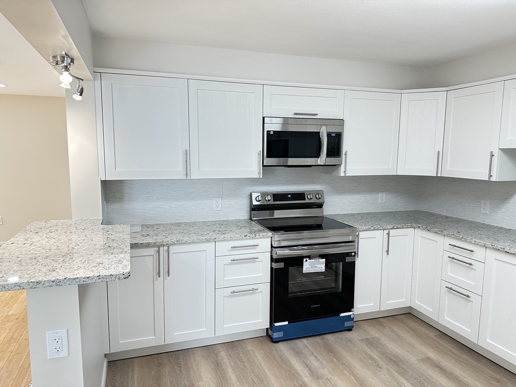 1004 Paradise Road, Unit 1K Swampscott, MA 01907 - Photo 7 of 37 a kitchen with granite countertop a stove and a microwave