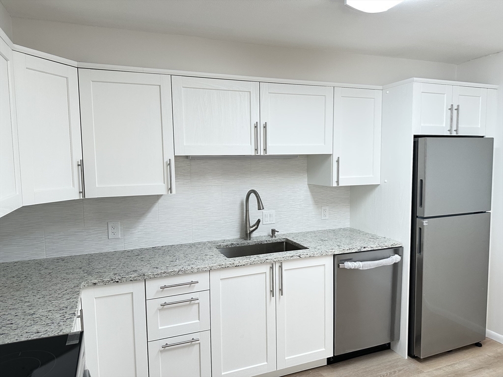 1004 Paradise Road, Unit 1K Swampscott, MA 01907 - Photo 8 of 37 a kitchen with granite countertop white cabinets and refrigerator