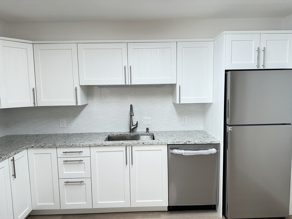 1004 Paradise Road, Unit 1K Swampscott, MA 01907 - Photo 10 of 37 a kitchen with stainless steel appliances granite countertop a refrigerator sink and cabinets