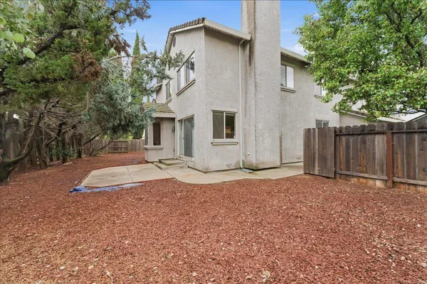 a backyard of a house with wooden fence and large trees