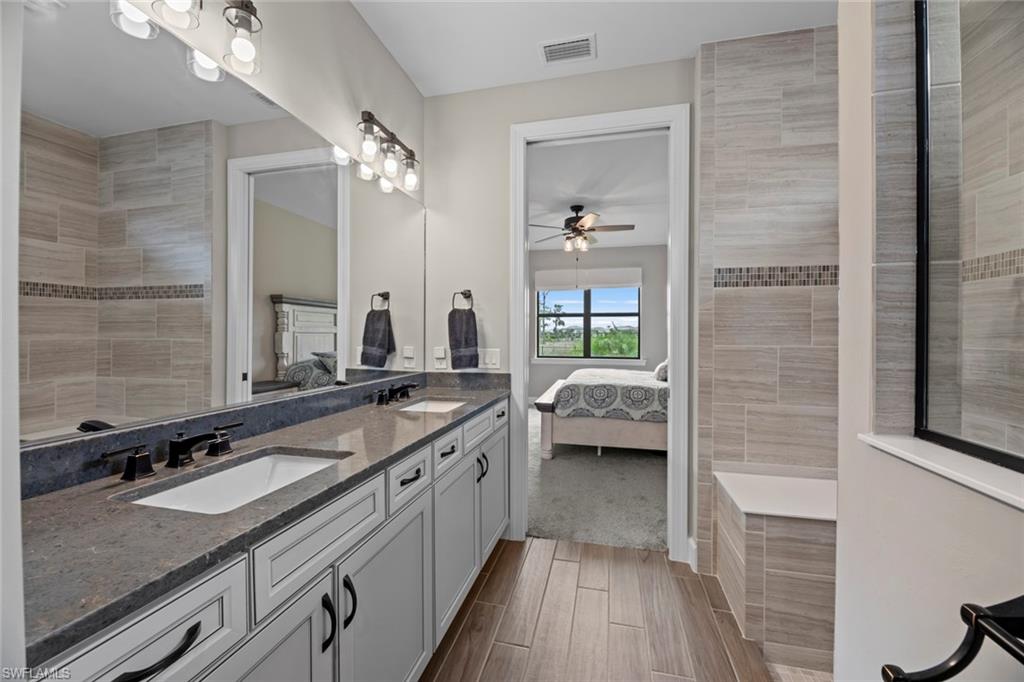 19648 Beechcrest Place Estero, FL 33928 - Photo 12 of 34 a en suite bathroom with a granite countertop sink a toilet a mirror and bathtub