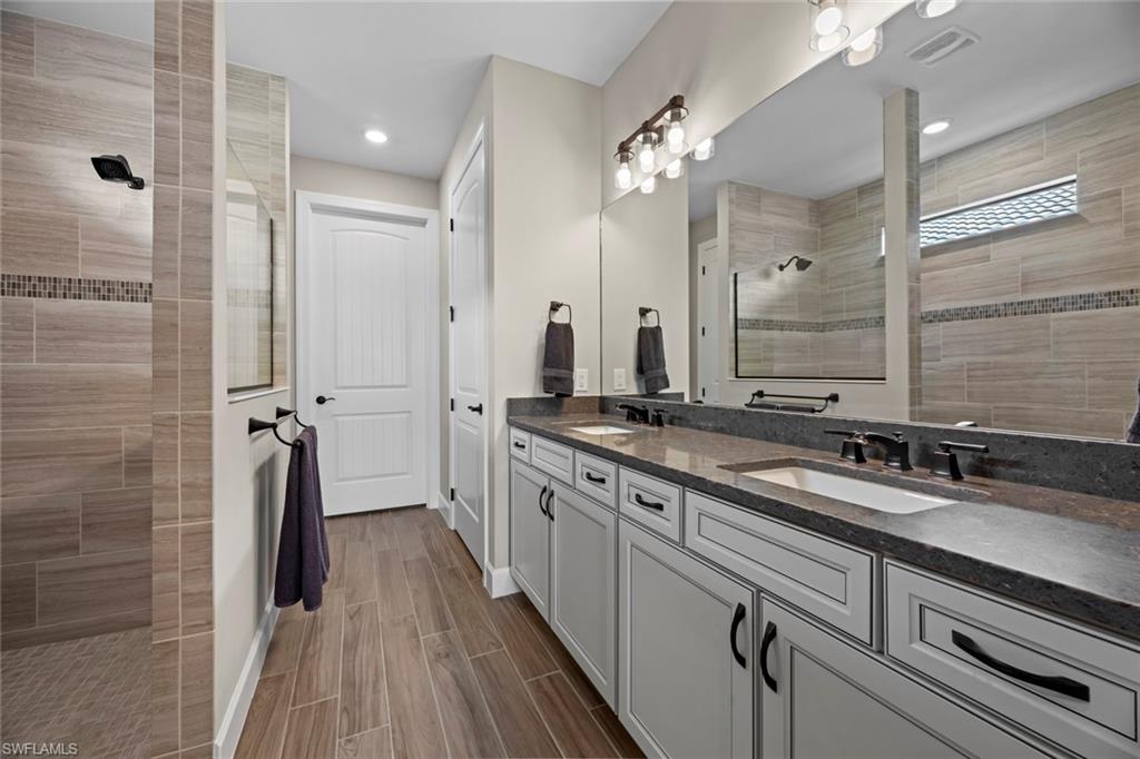 19648 Beechcrest Place Estero, FL 33928 - Photo 13 of 34 a bathroom with a double vanity sink a mirror and shower