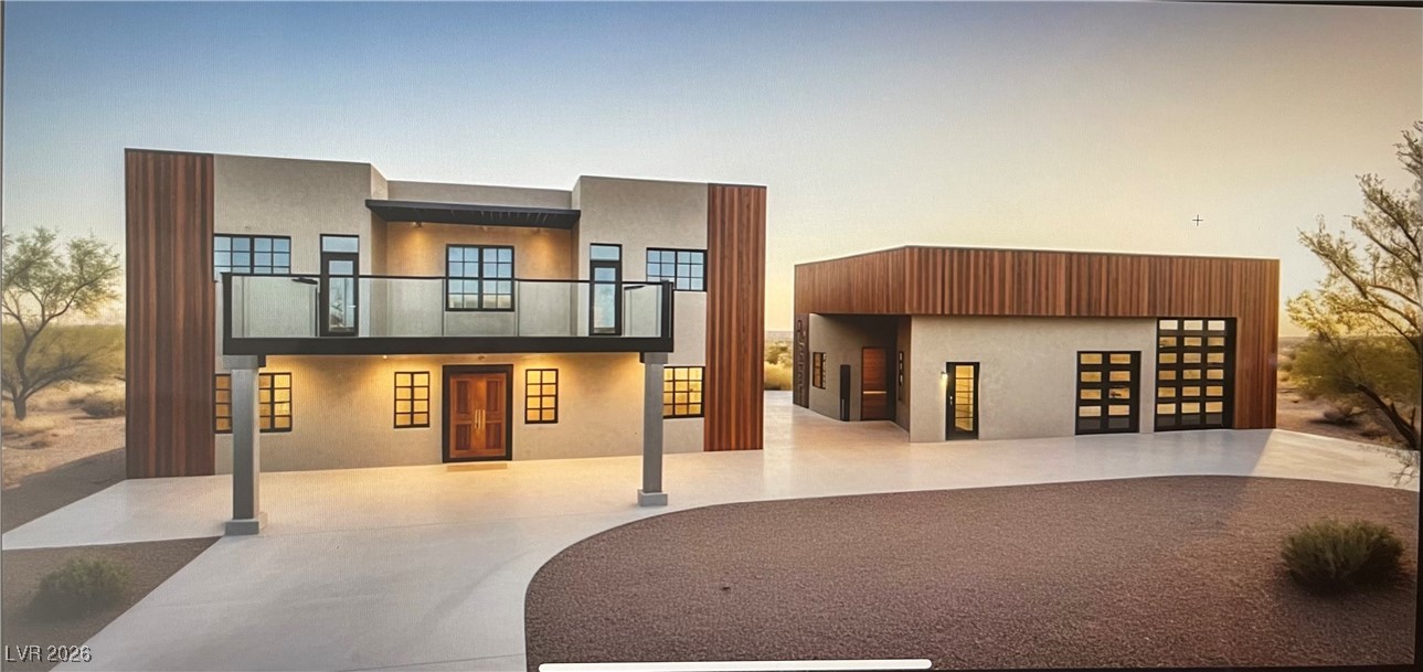 Modern home with a balcony, driveway, and stucco siding