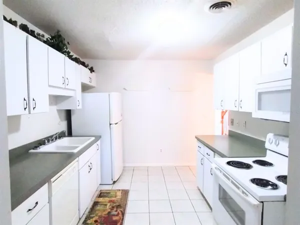 a kitchen with granite countertop white cabinets and white appliances