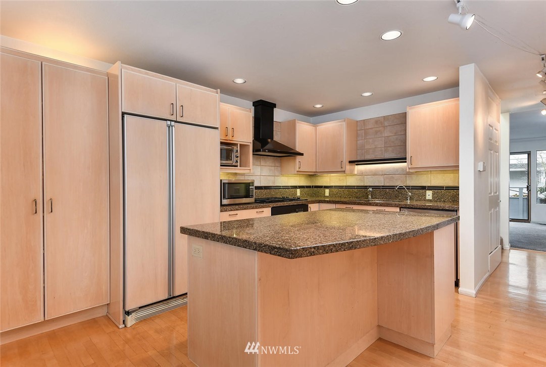623 Main Street, Unit 3 Edmonds, WA 98020 - Photo 7 of 10 a kitchen with stainless steel appliances granite countertop a refrigerator a stove and a sink with wooden floor