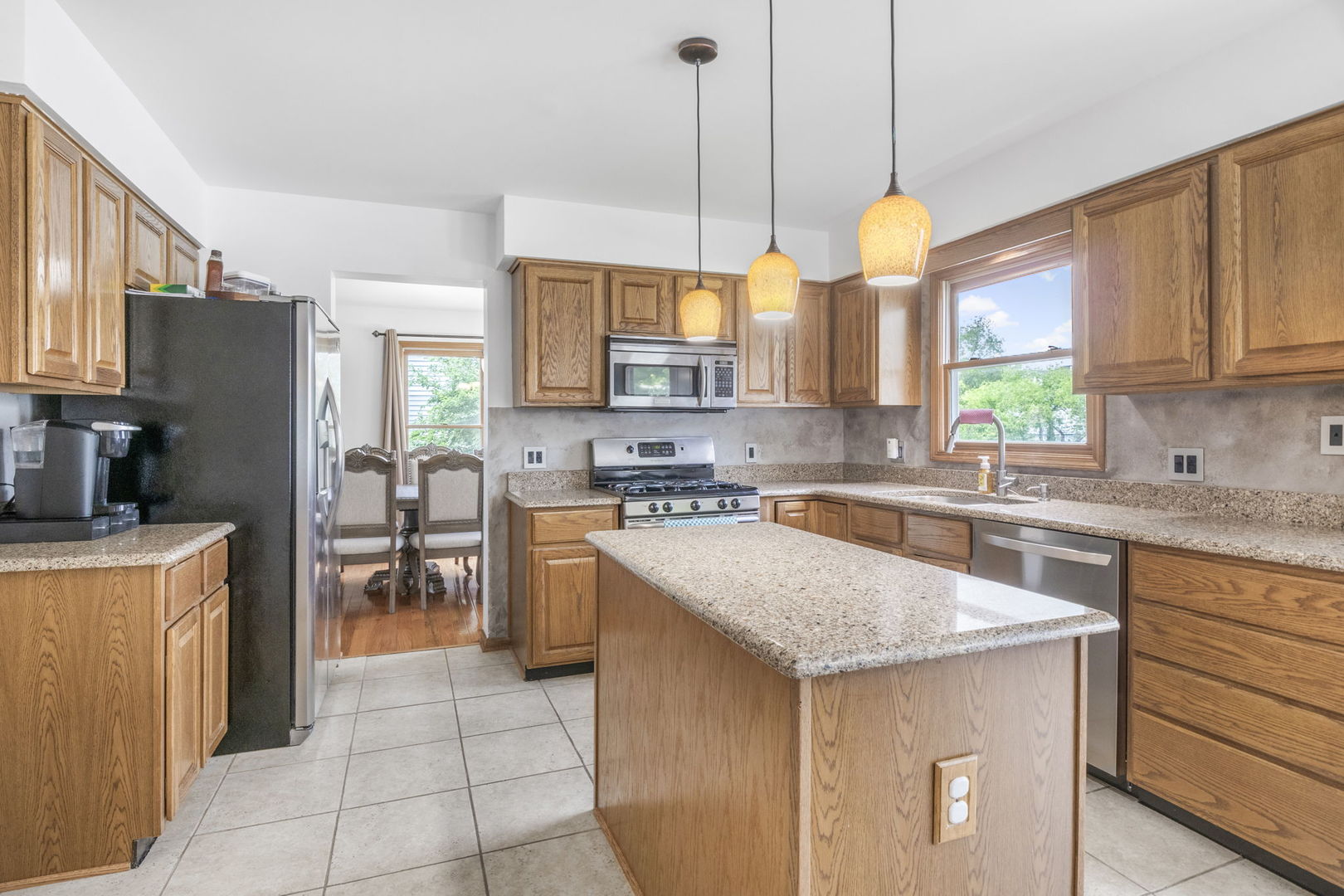 5207 Sunmeadow Drive Plainfield, IL 60586 - Photo 9 of 32 a kitchen with stainless steel appliances granite countertop a sink a stove a refrigerator a center island with wooden cabinets and floor