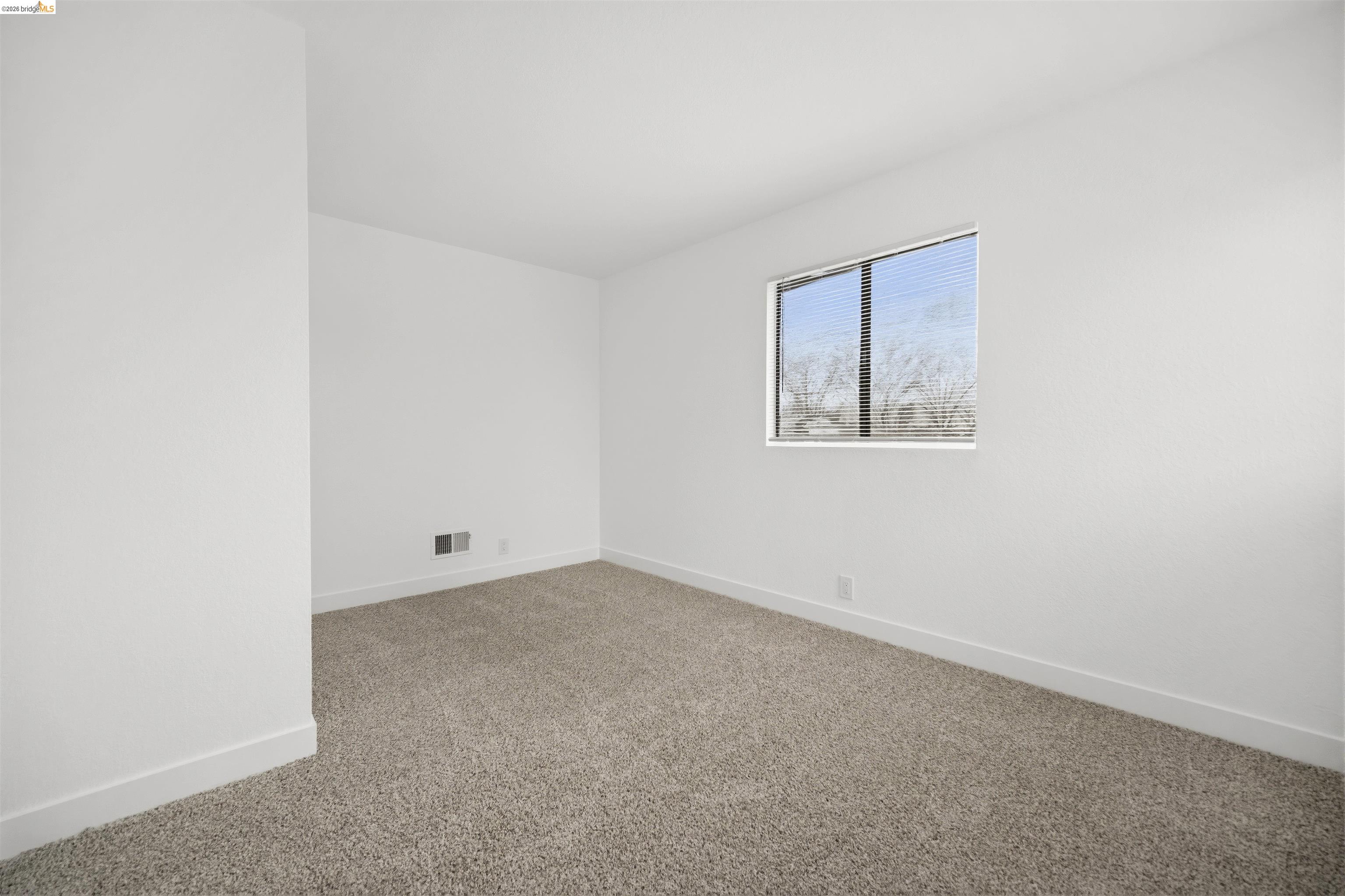 10933 Julius Street, Unit D Oakland, CA 94605 - Photo 14 of 28 Empty room featuring light colored carpet and baseboards