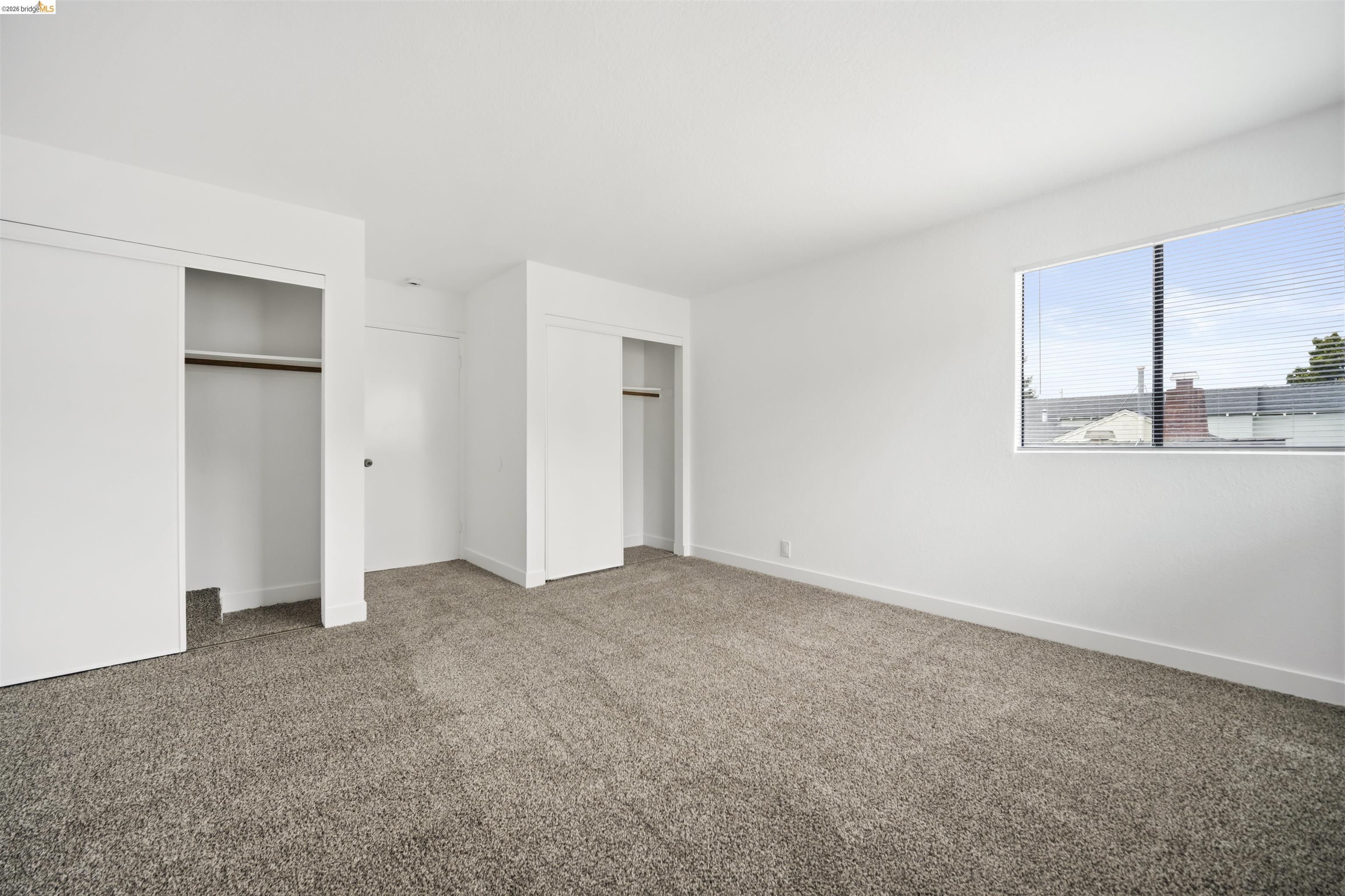 10933 Julius Street, Unit D Oakland, CA 94605 - Photo 20 of 28 Unfurnished bedroom featuring two closets and carpet flooring